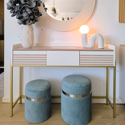 Móvel de apoio moderno com espelho redondo, vaso decorativo, candeeiro e duas banquetas azuis em veludo.