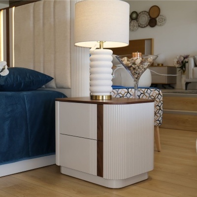 Mesa de cabeceira com candeeiro branco e cama azul
