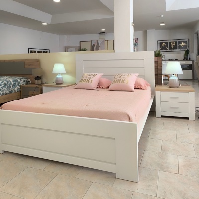 Cama branca com roupa de cama rosa e almofadas decorativas, mesas de cabeceira com lâmpadas em quarto moderno.