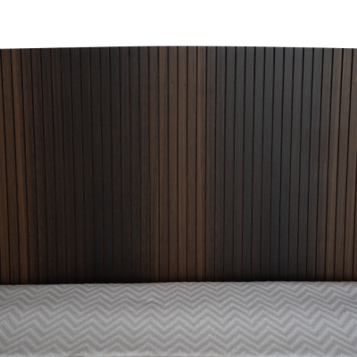 Cabeceira de cama em madeira escura com colcha cinza clara padrão ziguezague.