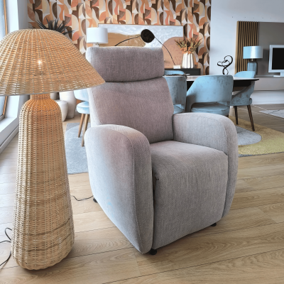 Poltrona cinza de tecido com lâmpada de vime ao lado em sala moderna