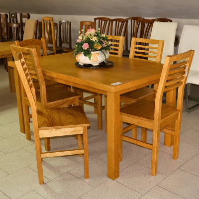 Conjunto de jantar em madeira clara com vaso de flores no centro da mesa
