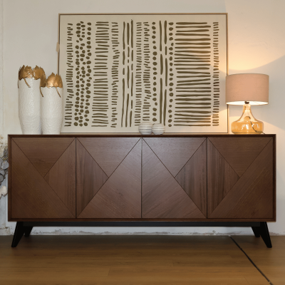 Aparador em madeira com decoração de jarras, esferas e lâmpada, parede com quadro abstrato em tons de bege e verde-oliva.