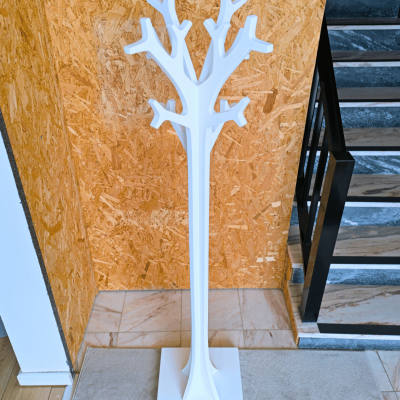 Cabide em forma de árvore branco junto a parede de madeira e escada