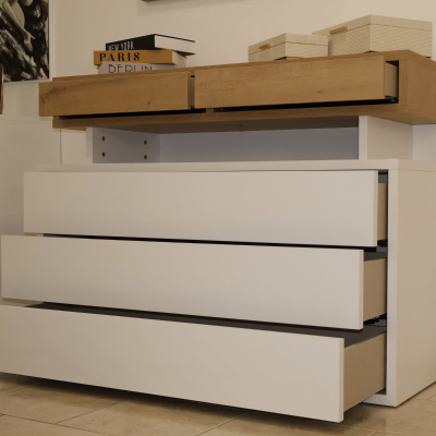 Cómoda moderna com gavetas brancas e em madeira clara com caixas em cima