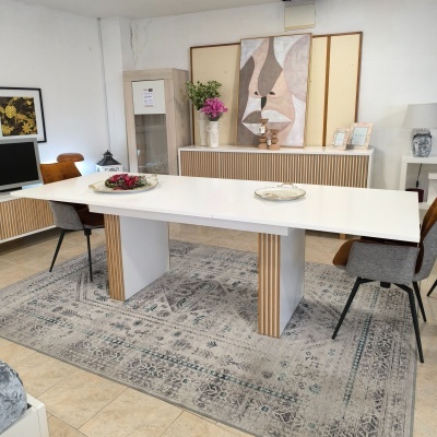 Mesa de jantar branca com pernas decoradas, cadeiras cinza e castanho, tapete cinza com padrão geométrico e decoração de interior