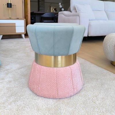 Pufe moderno rosa e azul com faixa dourada sobre tapete bege numa sala de estar