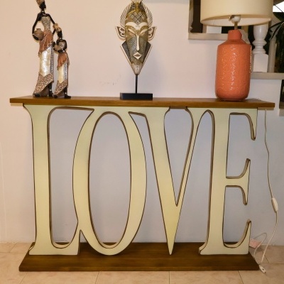 Aparador em madeira com palavra LOVE e decoração de estátuas, máscara e candeeiro