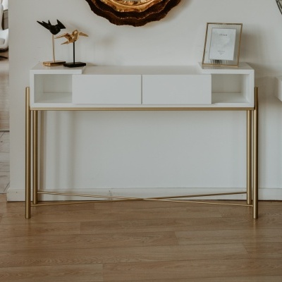 Consola branca com estrutura dourada, esculturas de pássaros e porta-retratos na parte superior.