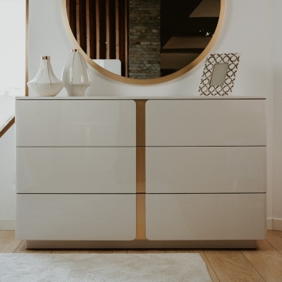 Cômoda branca com gavetas e espelho redondo decorada com garrafas de vidro e porta-retratos