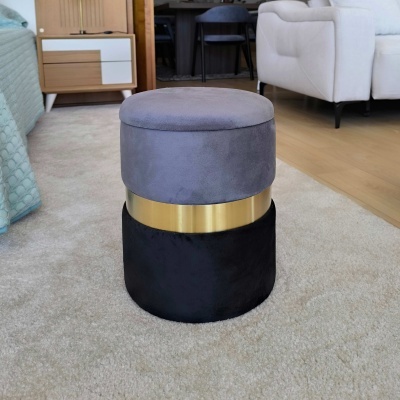 Pufe redondo cinzento, dourado e preto em tapete claro no interior