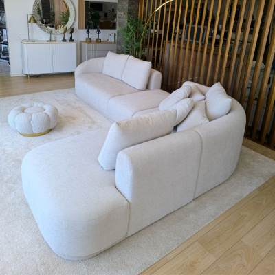 Sofá modular branco em ambiente interior com pufe arredondado e decoração moderna