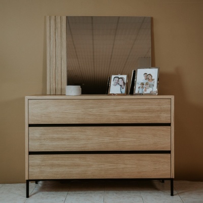 Cómoda de madeira clara com espelho e objetos decorativos sobre ela