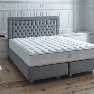 Cama de casal com colchão branco e cabeceira cinza com padrão capitonê