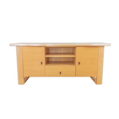 Móvel baixo de madeira clara com portas, prateleiras e gaveta