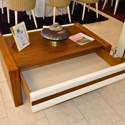 Mesa de centro em madeira com gaveta branca aberta e decoração em piso de azulejo