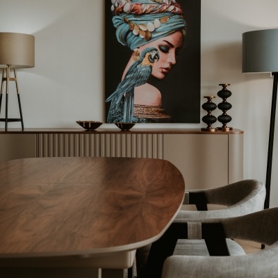 Sala de jantar com mesa de madeira, cadeiras cinza, luminárias de pé e quadro decorativo na parede