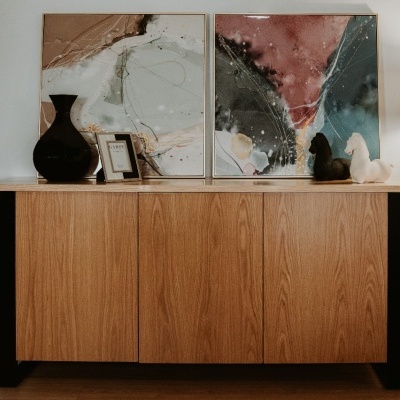 aparador de madeira clara com objetos decorativos e candeeiro de pé