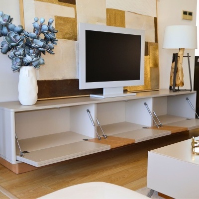 Aparador branco com televisor, vaso com flores azuis e lâmpada de base madeira