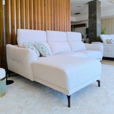 Sofá chaise longue creme claro com almofadas verdes e brancas numa sala moderna