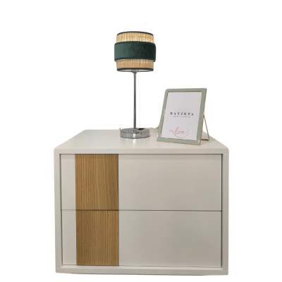 Cômoda branca com detalhe em madeira, candeeiro verde com riscas creme e moldura prateada com texto