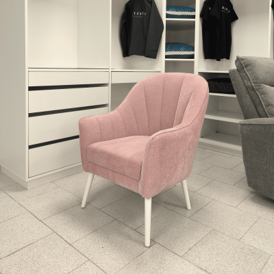 Cadeira rosa claro estofada com pernas brancas numa sala com armários brancos e roupa pendurada