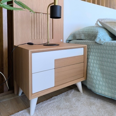 Mesa de cabeceira de madeira e branco ao lado de cama com colcha verde água