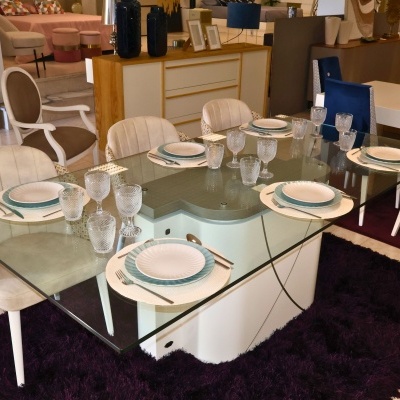 Mesa de jantar com tampo de vidro, cadeiras bege e louça branca e azul