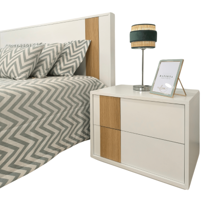 Cabeceira branca com detalhe em madeira, mesa de cabeceira branca com detalhe em madeira, roupa de cama cinzenta com padrão ziguezague e abajur com cúpula bege e preta