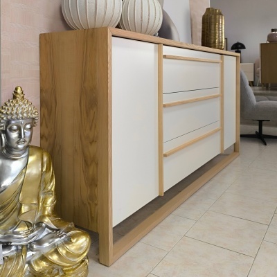 Aparador de madeira clara com frentes brancas e decoração ao redor