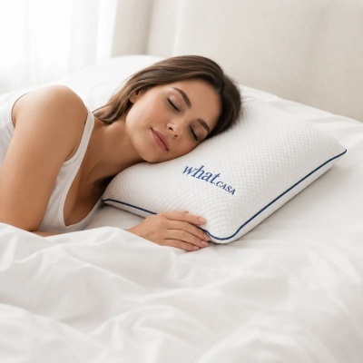 Mulher a dormir com a cabeça descansada num travesseiro branco com borda azul e texto what CASA