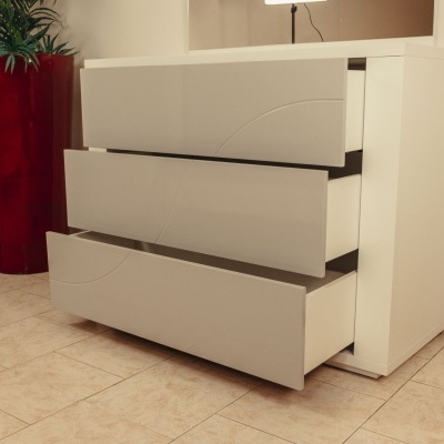 Cómoda branca com três gavetas abertas perto de vaso vermelho com planta