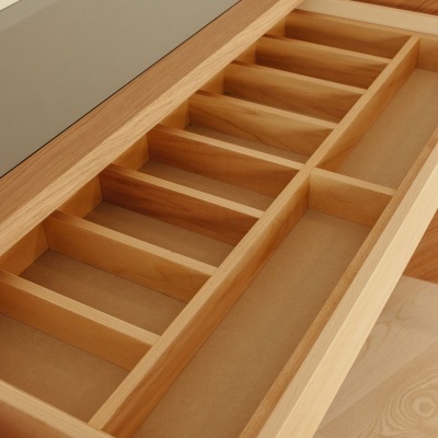 Gaveta de madeira clara com divisórias internas e tampo em vidro fosco.