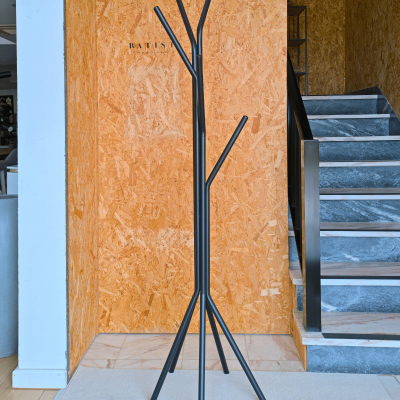 Cabideiro de pé preto em design moderno, junto a parede de madeira clara e escada azul