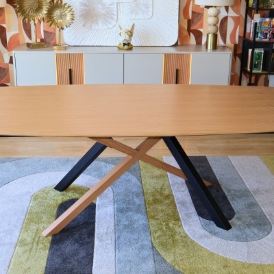 Mesa de madeira com pés em cruz sobre tapete colorido