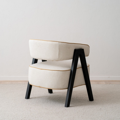 Cadeira estofada bege com estrutura preta colocada sobre tapete claro