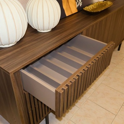 Móvel de madeira escura com gaveta aberta e decoração