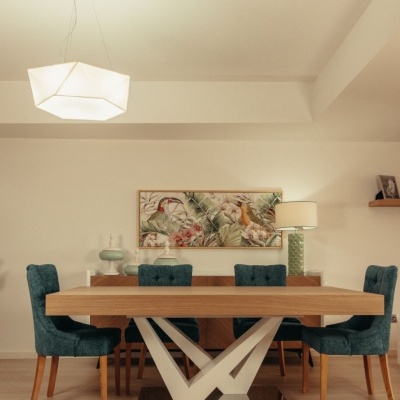 Mesa de jantar em madeira clara com cadeiras azul turquesa e candeeiro branco numa sala moderna