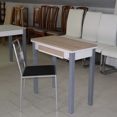 Mesa de madeira clara com pernas cinza e cadeira metálica com assento preto num ambiente de móveis