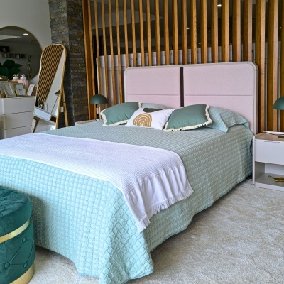 Cama de casal com cabeceira rosa e roupa de cama azul claro e verde