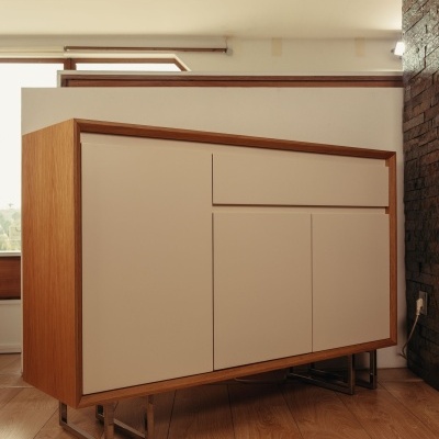 Móvel de arrumação em madeira clara com portas creme e base metálica