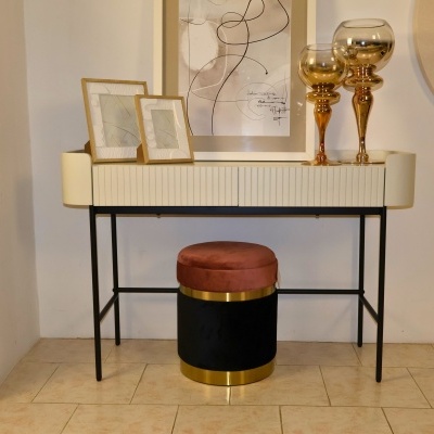 Móvel creme com molduras douradas, castiçais e puff preto com assento castanho