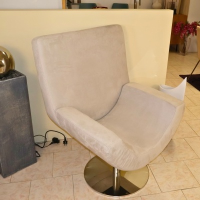 Cadeira giratória estofada bege com base metálica redonda em espaço interior