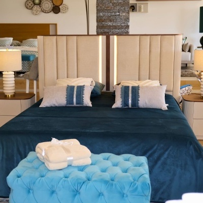 Quarto com cama de cabeceira estofada bege e cobertor azul escuro