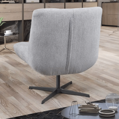 Poltrona giratória cinza estofada com base preta numa sala com chão de madeira e mesa de apoio.