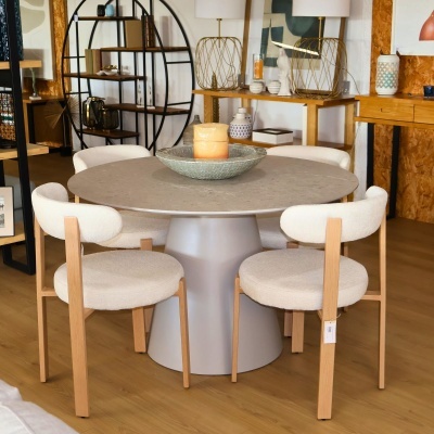 Mesa redonda cinzenta com quatro cadeiras brancas de madeira em interior decorado