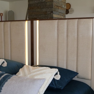 Cabeceira estofada bege com luz LED e almofadas decorativas azuis e bege