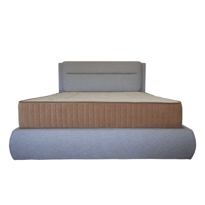 Cama estofada cinzenta com colchão castanho e bege vista de frente