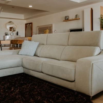 sofá bege em couro com chaise longue e almofada cinza numa sala de estar