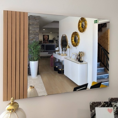 Espelho grande com moldura de madeira listrada refletindo interior decorado